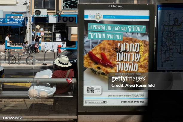 Person sits at a bus stop that is not operational due to the Shavuot holiday on June 05, 2022 in Tel Aviv, Israel. Beaches were packed in part due to...