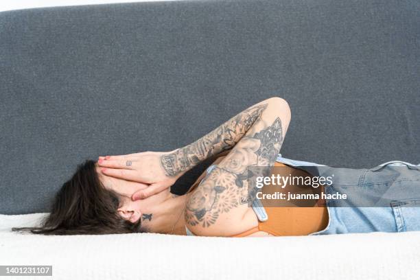 woman going through a difficult time in her life, lying on the sofa at home. - woman head in hands sad stock pictures, royalty-free photos & images