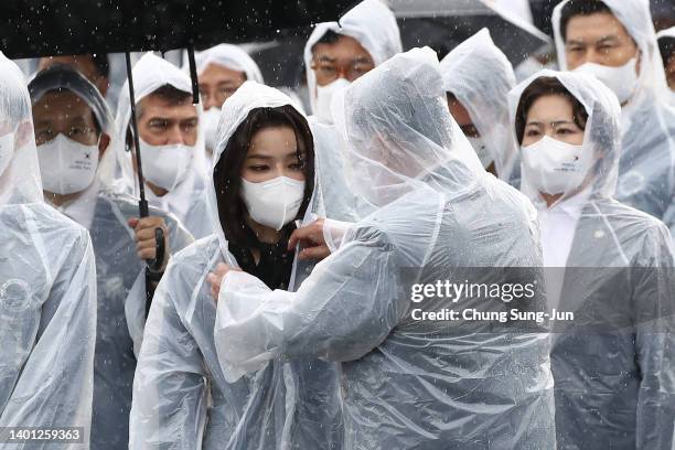 South Korean President Yoon Suk-yeol adjusts his wife Kim Keon-hee's raincoat during a ceremony marking Korean Memorial Day at the Seoul National...