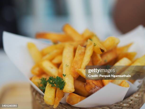 closeup french fries, potato chips yellow crispy fries in wooden basket on white table, snack delicious food - fast food french fries stock pictures, royalty-free photos & images