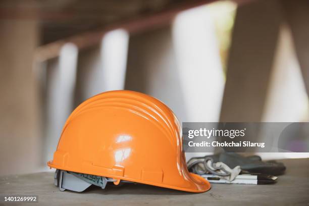 safety helmet with blueprint, gloves on the construction site - schutzhelm stock-fotos und bilder