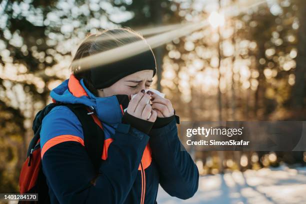 female hiker blowing her nose while standing in winter forest - cold virus stock pictures, royalty-free photos & images