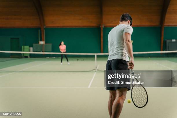 young male instructor bouncing ball while holding racket before serving - warm up exercise indoor stock pictures, royalty-free photos & images