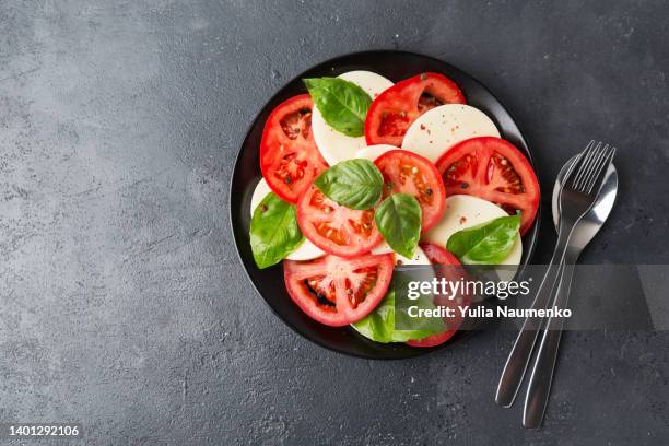 caprese salad made of sliced fresh tomatoes, mozzarella cheese and basil. - caprese stockfoto's en -beelden