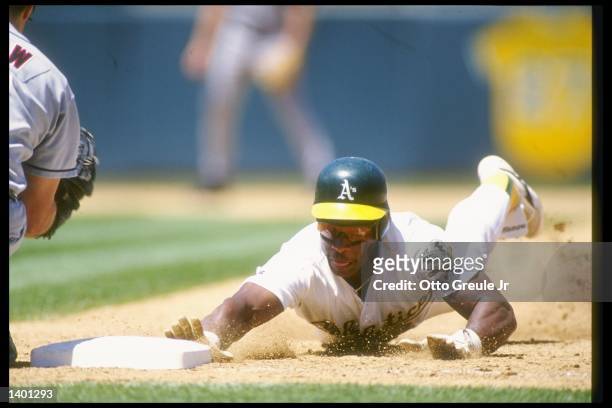 Outfielder Rickey Henderson of the Oakland Athletics slides into base during a game against the California Angels at the Oakland Coliseum in Oakland,...