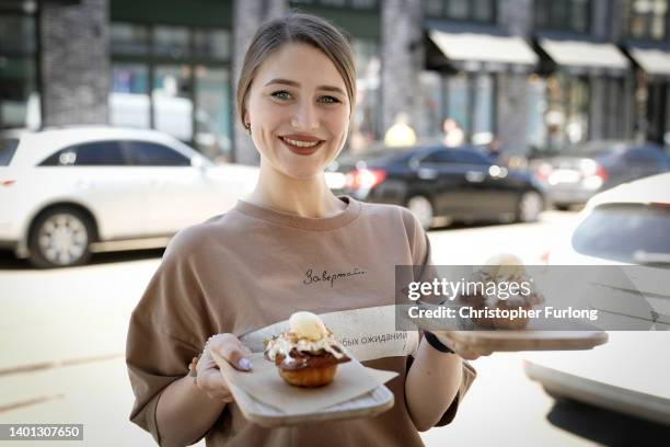 Waitress Daniella poses with cakes named after British Prime Minister Boris Johnson at the Zavertailo Cafe, one of Kyiv's top artisan bakeries on...