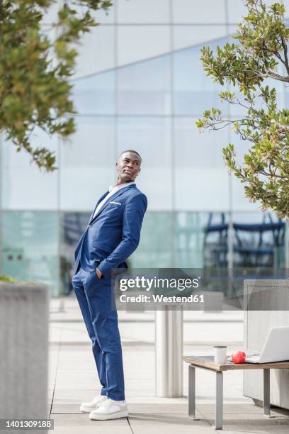 businessman with hands in pockets leaning backwards on footpath - bending over backwards stock pictures, royalty-free photos & images