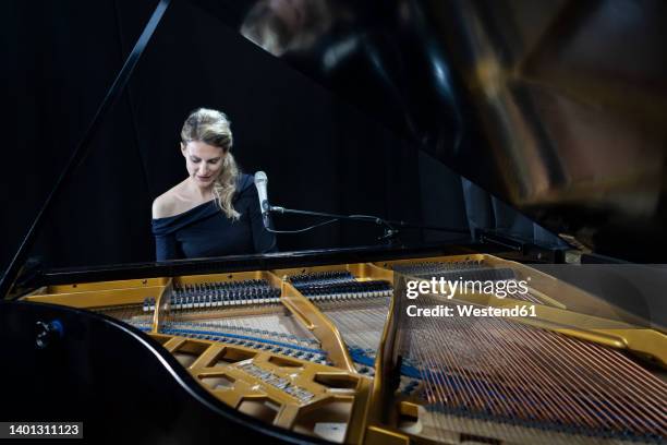 mature pianist playing grand piano against black background - pianist front stock pictures, royalty-free photos & images