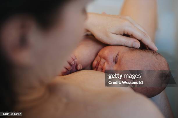 baby sleeping on mother's chest in bathroom at home - home birth stock-fotos und bilder