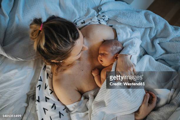 baby sleeping on mother's chest in bed at home - neu stock-fotos und bilder