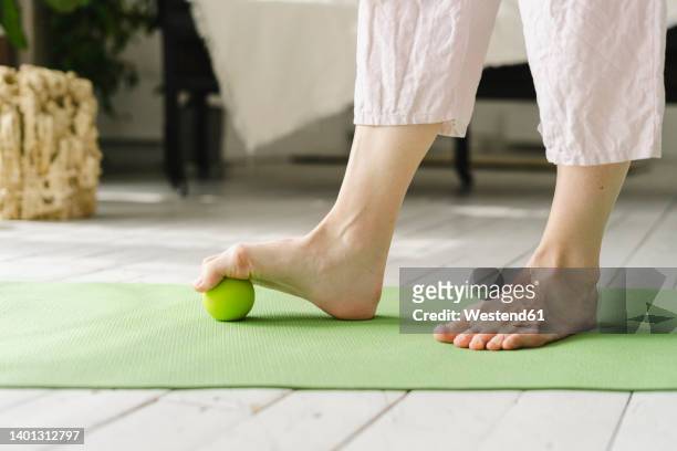 woman stepping on ball with bare foot at home - lower stock pictures, royalty-free photos & images