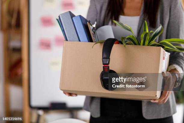 businesswoman holding a cardboard box with personal belongings - bezittingen stockfoto's en -beelden