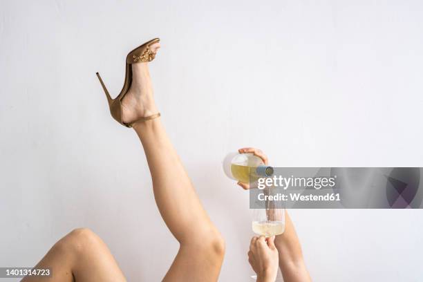 woman wearing high heels pouring wine in wineglass - hand pouring stock pictures, royalty-free photos & images