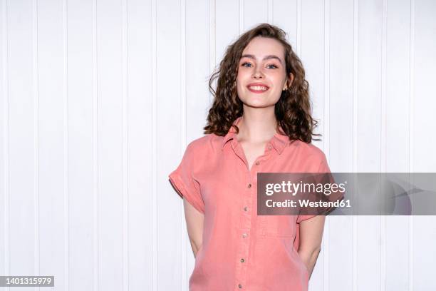 happy woman standing in front of white wall - flash stockfoto's en -beelden