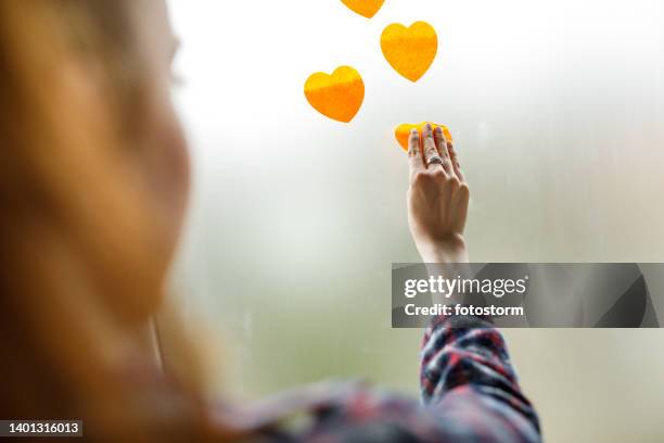 businesswoman applying heart shaped sticky notes on a window - grafisch ontwerpbureau stockfoto's en -beelden