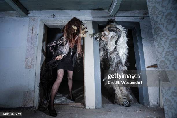 monster and witch looking at each other standing at doorway of horror house - krampus stock pictures, royalty-free photos & images