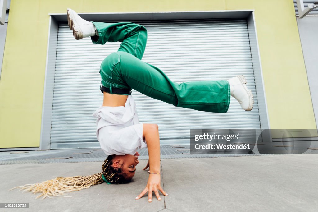 Young woman doing headstand in front of shutter