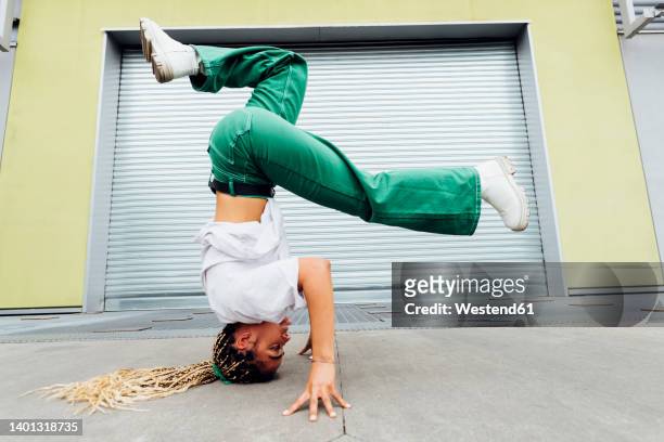 young woman doing headstand in front of shutter - break photos et images de collection