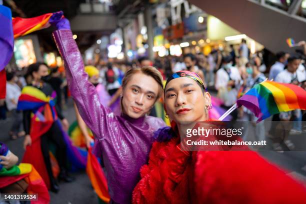 gay asian couple smiling and taking a selfie enjoying  pride parade. - aapi protest stock pictures, royalty-free photos & images