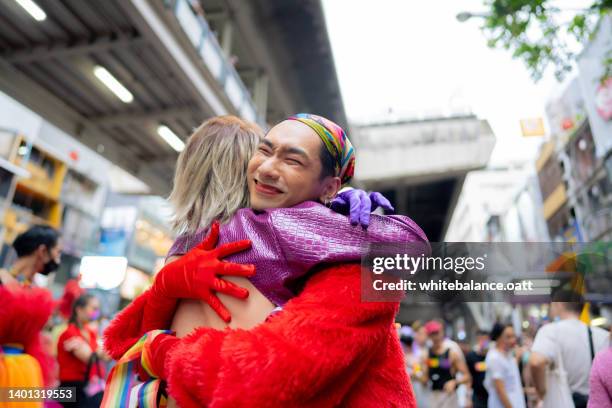 happy asian couple having fun in the street lgbtq pride parade. - pride stock pictures, royalty-free photos & images