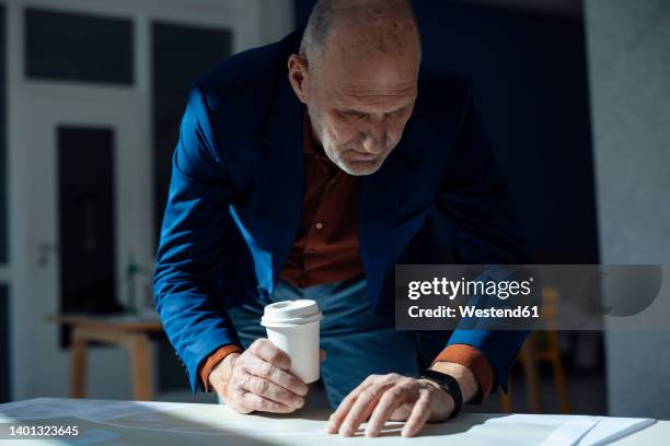 businessman holding disposable cup checking time on smart watch at desk - receding stock pictures, royalty-free photos & images