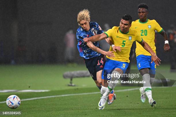 Junya Ito of Japan and Casemiro of Brazil compete for the ball during the international friendly match between Japan and Brazil at National Stadium...