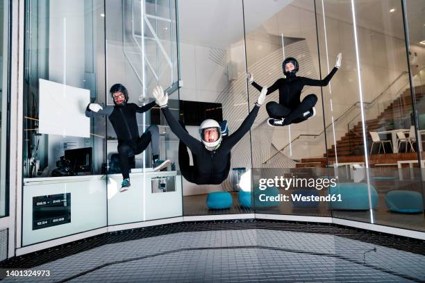 happy man with friends flying in wind tunnel - indoor skydive stock pictures, royalty-free photos & images