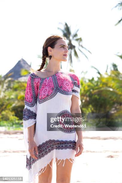 woman looking away at beach on sunny day - tunic woman stock pictures, royalty-free photos & images