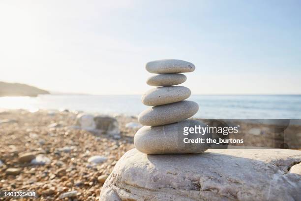 stack of balanced stones at beach against clear sky - équilibre photos et images de collection