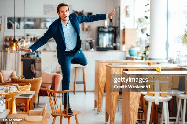 businessman with arms outstretched standing on chair at cafe - pretending to be a plane stock pictures, royalty-free photos & images