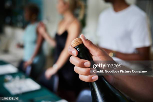 junger mann, der während einer dinnerparty mit freunden eine flasche champagner öffnet - sektkorken stock-fotos und bilder