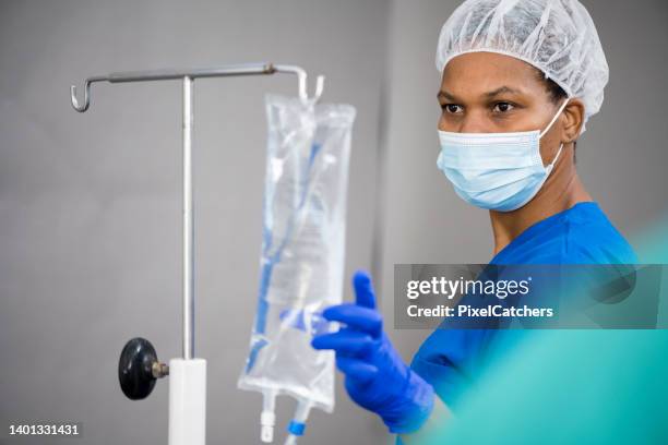 nurse hanging iv drip on stand - nurse with surgical mask stock pictures, royalty-free photos & images