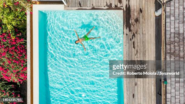 happy little boy enjoying floating in a pool, overhead view - drijven stockfoto's en -beelden