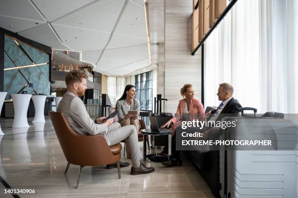 four colleagues sitting in a luxury hotel lobby and preparing for a business meeting. - luxury business travel stock pictures, royalty-free photos & images