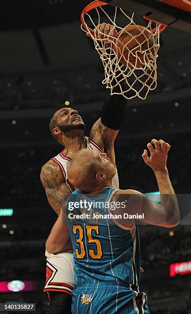 Carlos Boozer of the Chicago Bulls dunks the ball over Chris Kaman of the New Orleans Hornets at the United Center on February 28, 2012 in Chicago,...