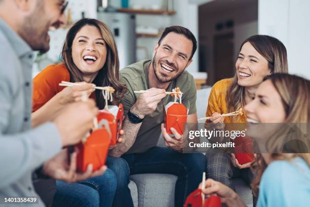 group of smiling friends eating chinese takeout food together - chinese takeout stock pictures, royalty-free photos & images
