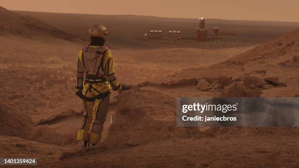 astronaut on planet mars watching a space station. earth colony in space - cosmonaut stock pictures, royalty-free photos & images