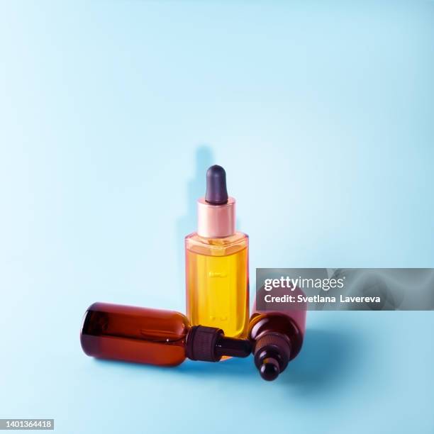 many glass dropper bottles with a pipette with black rubber tip on the blue background. nature skin concept. organic spa cosmetics. trendy concept. front view. - antioxidants skin stock pictures, royalty-free photos & images