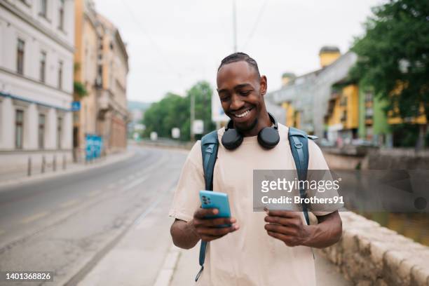 glücklicher junger mann, der ein smartphone im freien benutzt - mobile app stock-fotos und bilder
