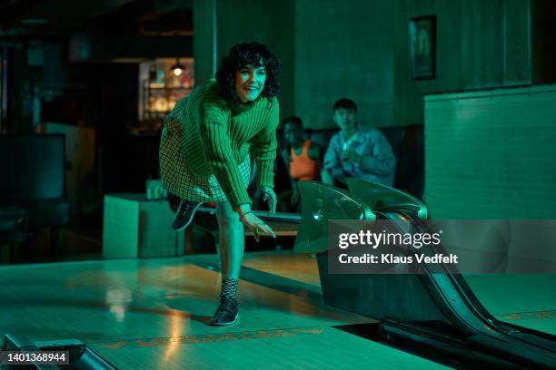 woman playing while friends in background - ten pin bowling foto e immagini stock
