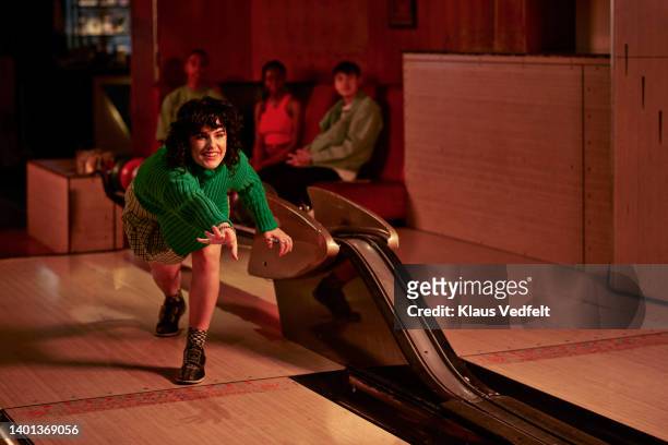 woman playing with friends in background - bowlingbahn stock-fotos und bilder