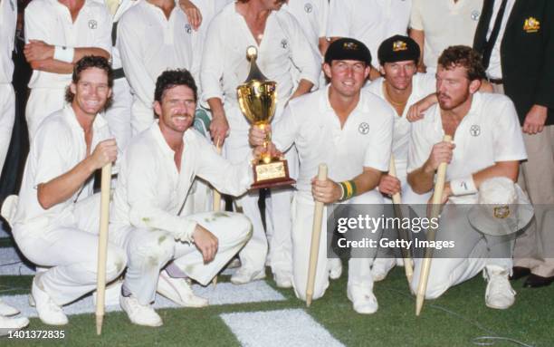 Australia Captain Allan Border holds the trophy with Geoff Marsh as Dean Jones Craig McDermott and Steve Waugh look on as Australia celebrate winning...