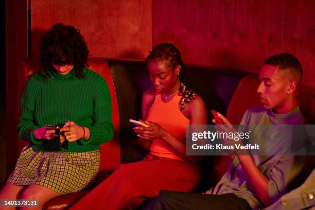 female and male friends using smart phones - three people on couch stock pictures, royalty-free photos & images