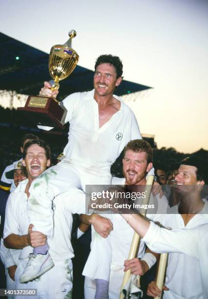 Australia Captain Allan Border holds the trophy with support from Dean Jones Craig McDermott and Steve Waugh as Australia celebrate winning the 1987...