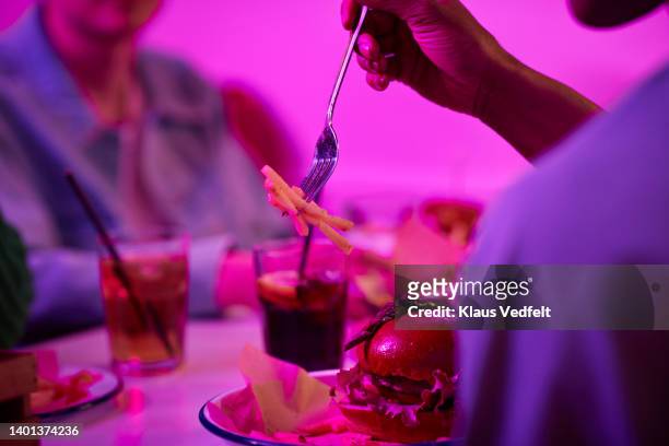 man having french fries with male friend - male burger eating fotografías e imágenes de stock