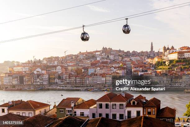 cable car cabins moving above porto city and douro river at sunset, portugal - porto portugal fotografías e imágenes de stock