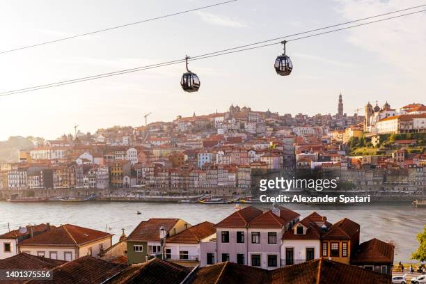 cable car cabins moving above porto city and douro river at sunset, portugal - portugal ストックフォトと画像