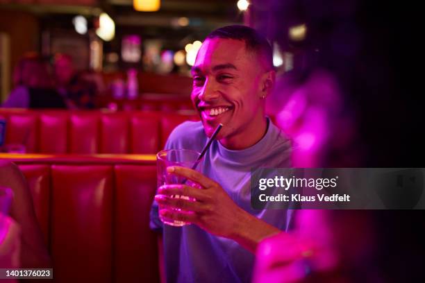 young man having drink sitting on sofa - amigos hombres en restaurant fotografías e imágenes de stock