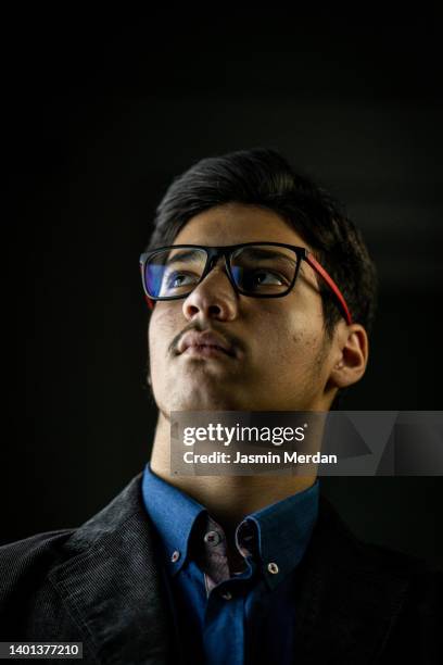 teenage boy portrait face in black background - hispanic man profile hopeful stock-fotos und bilder