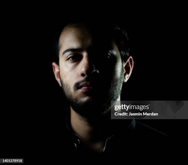 adult man portrait in shadows, black background - studio portrait dark background stock-fotos und bilder